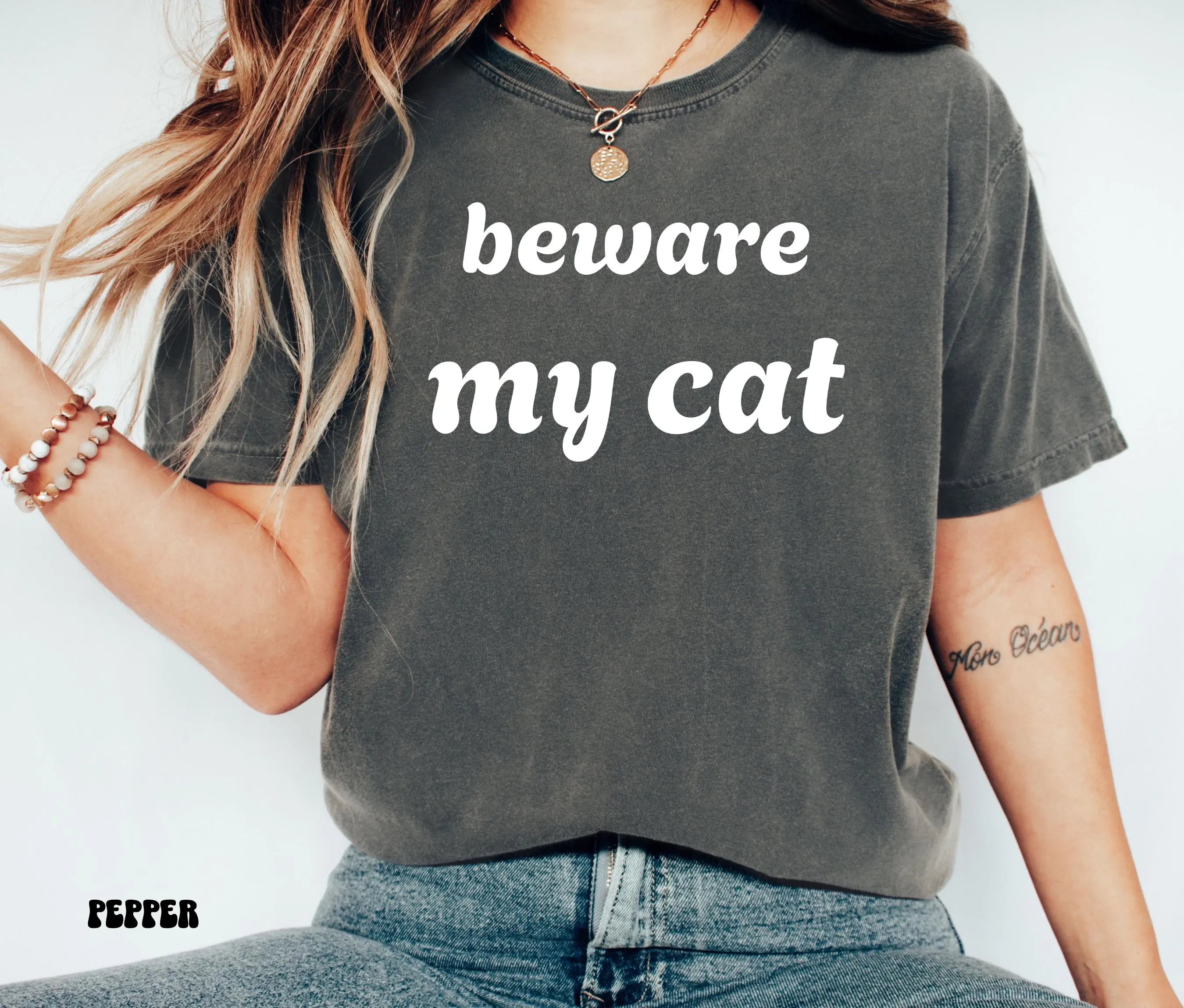 Woman wearing dark grey pepper t shirt with white text beware my cat as a funny cat lover gift