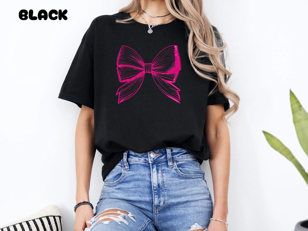 Person wearing a black t-shirt with a pink bow design on a white background