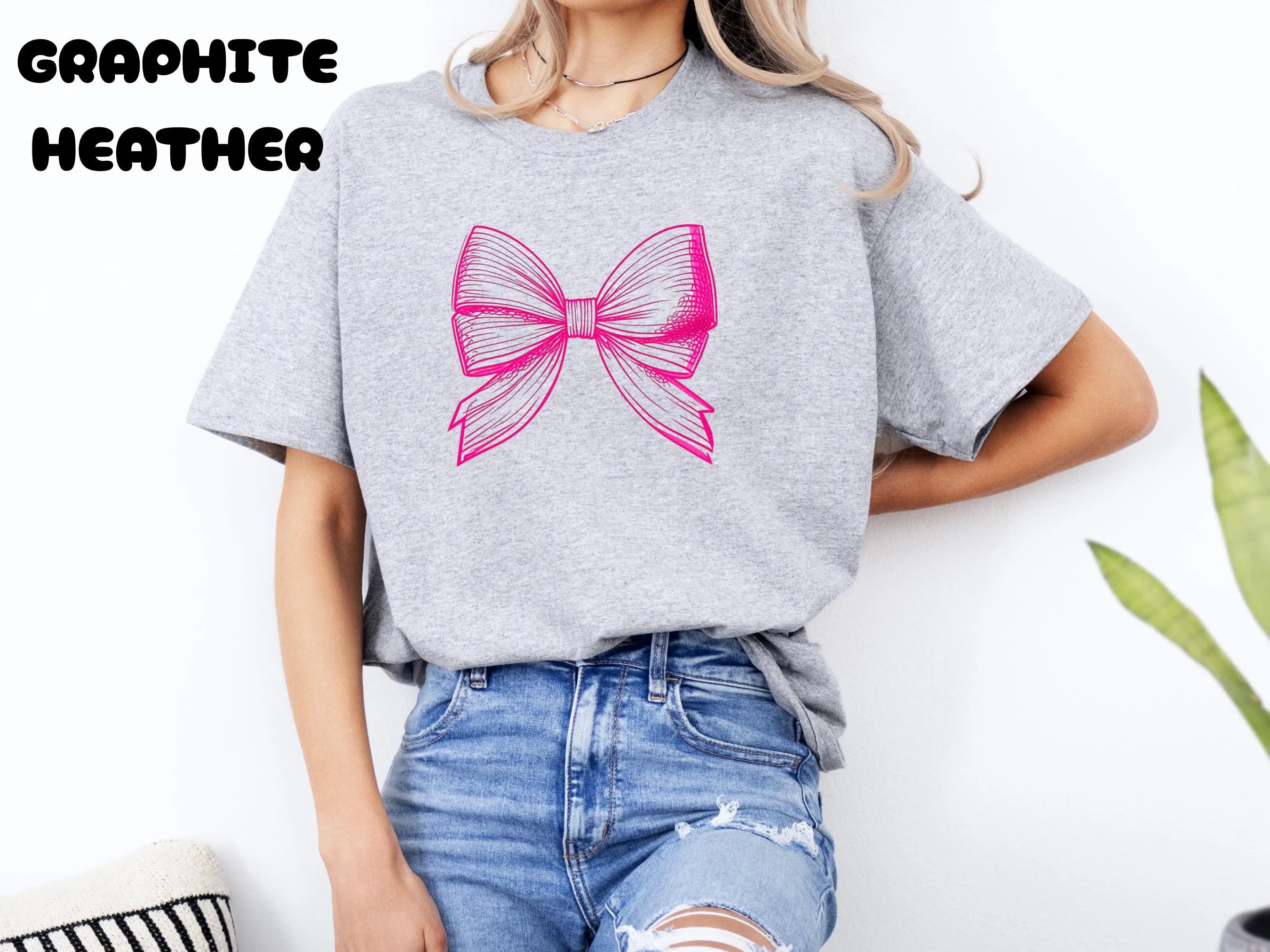 Person wearing a gray t-shirt with a pink bow design on a white background