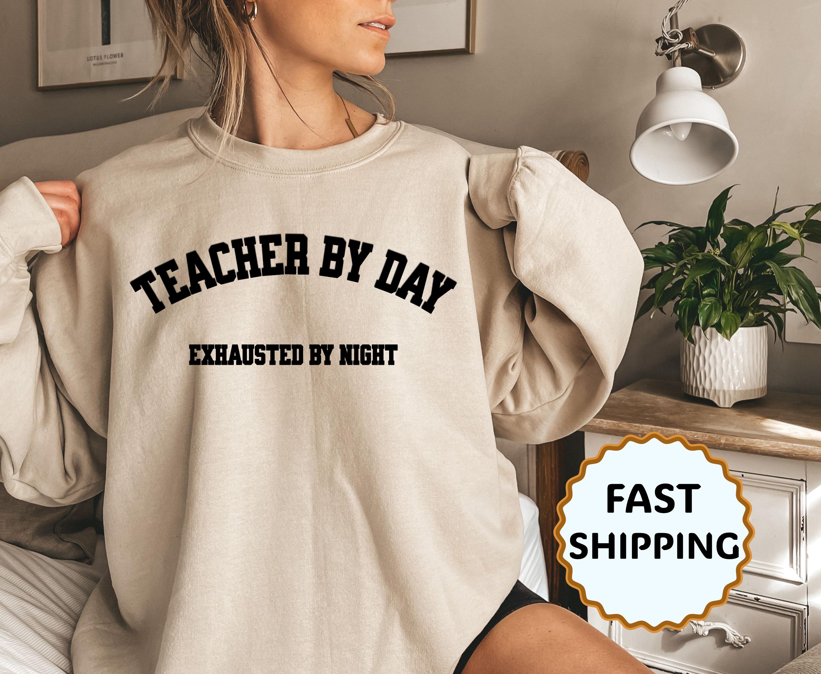 Person wearing a beige sweatshirt with text, sitting in a room with a plant and lamp.