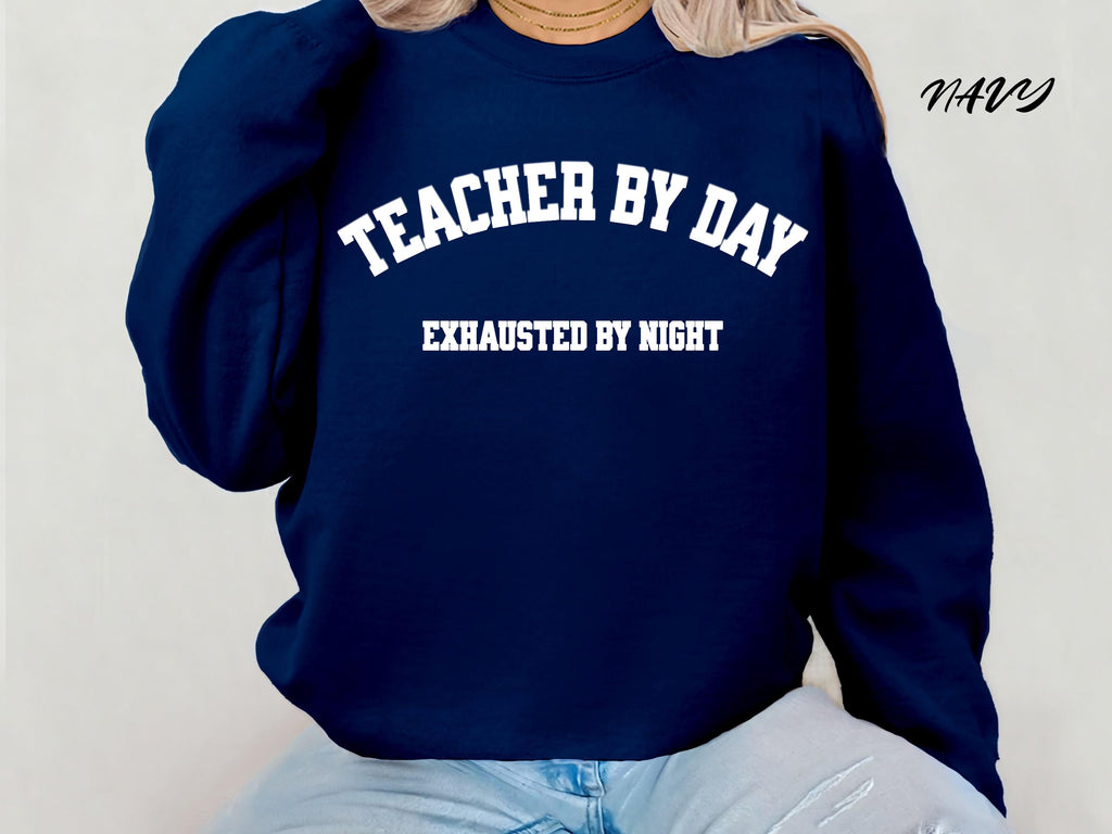 Navy sweatshirt with 'Teacher by Day, Exhausted by Night' text on a plain background